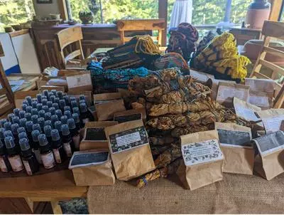 Teas, smudge sticks, and other items in bottles and bags sit on a table. The items were made in a 13 Moons plant workshop.